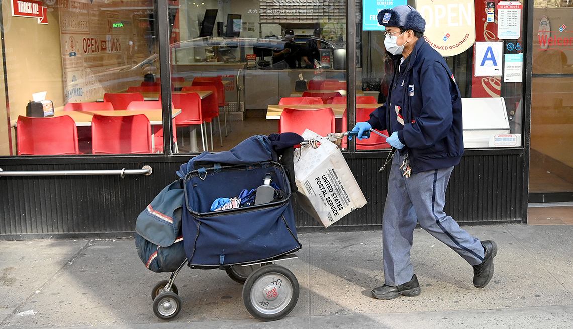 A mail carrier walking down the street with bags of mail