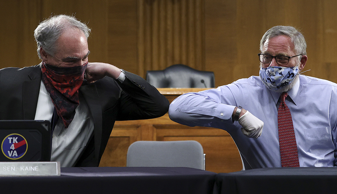 two senators bump elbows while wearing face masks at a hearing
