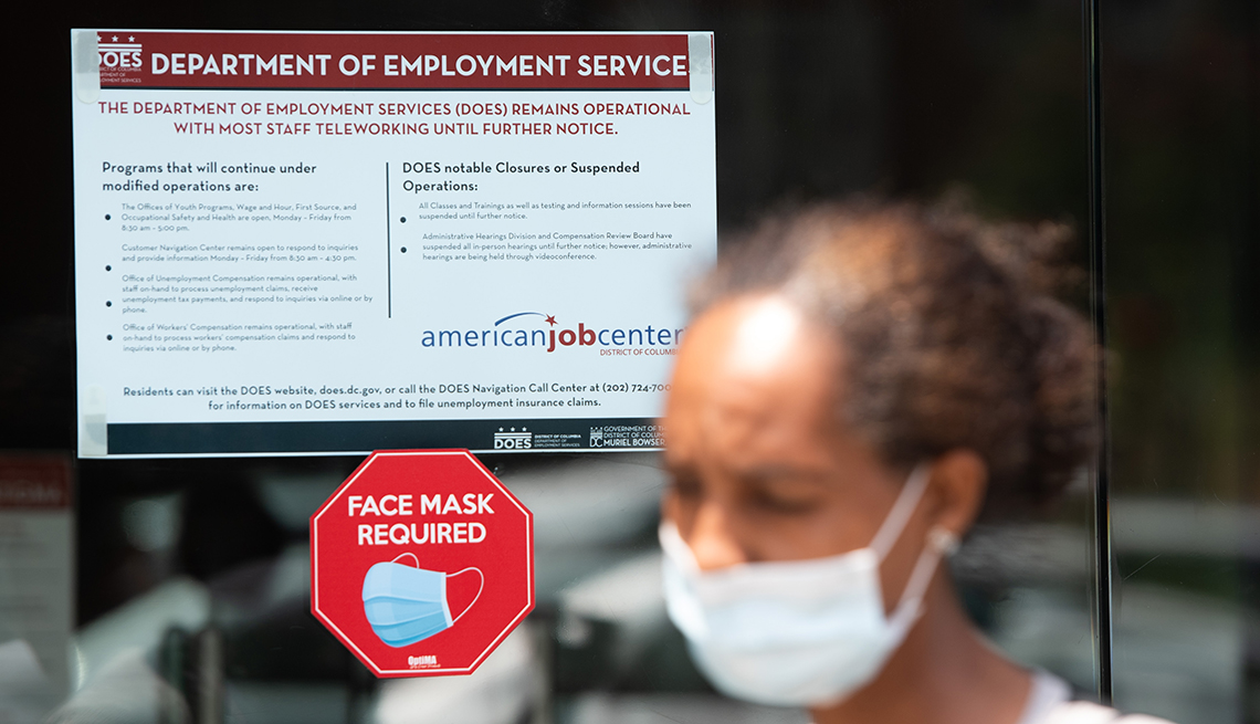 A woman walks out of a employment services building with a mask on
