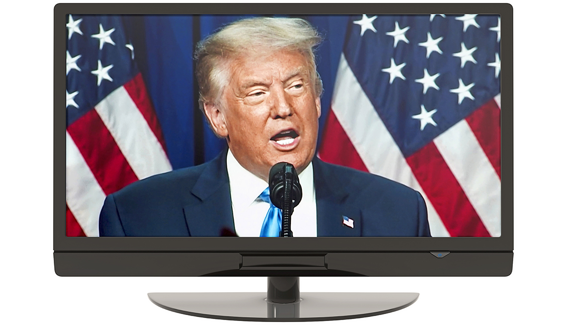 Imagen de Donald Trump en un monitor mientras habla en un discurso frente al micrófono