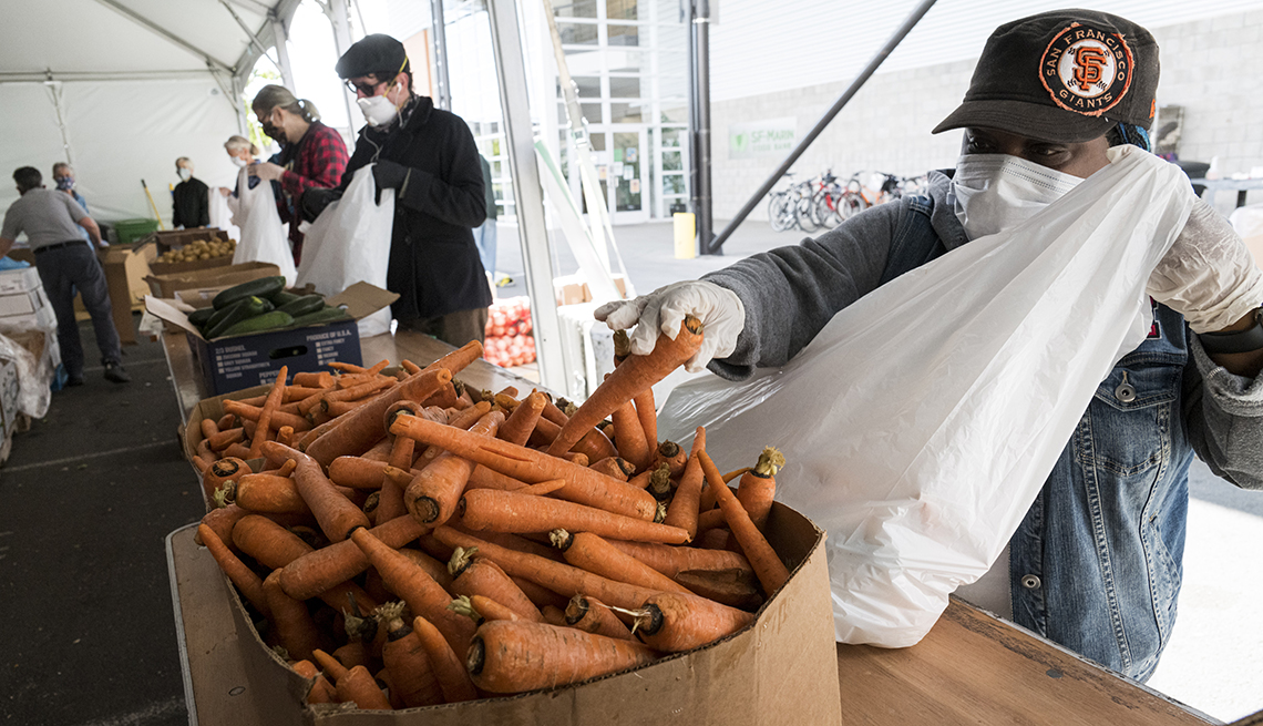 A woman is putting a carrot into a bag