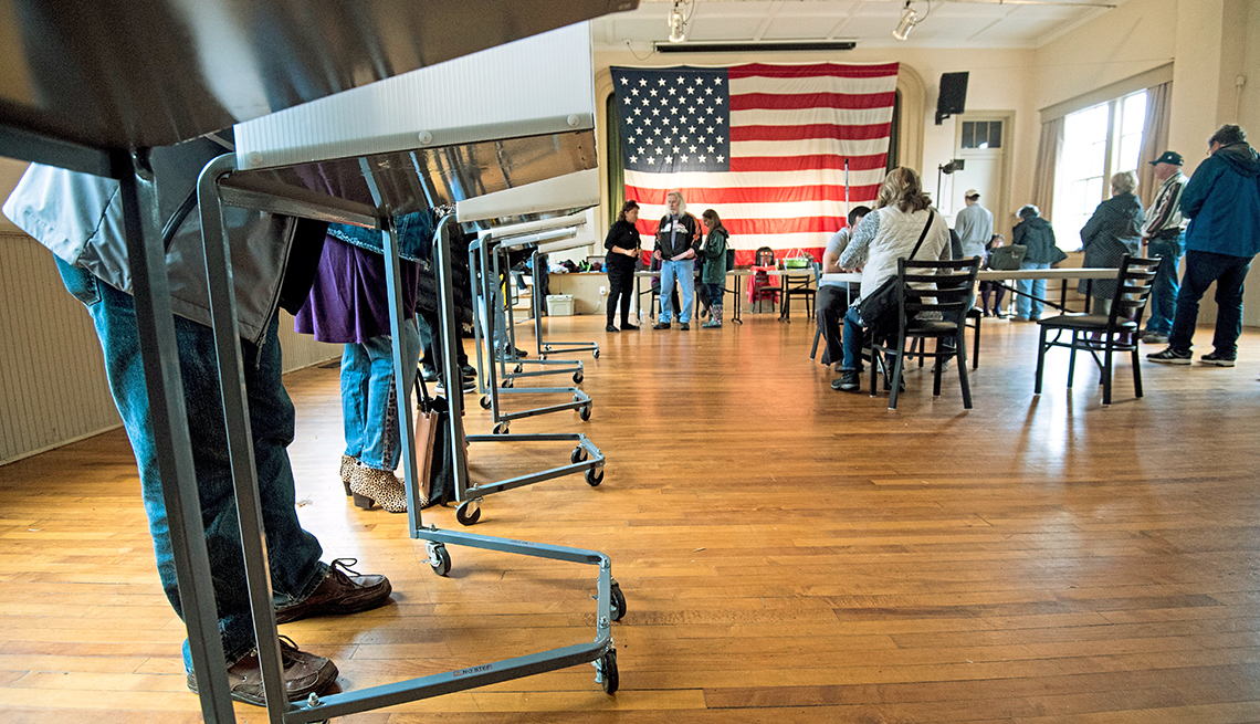 Vista de un sitio electoral mientras algunas personas están de pie en las cabinas de votación