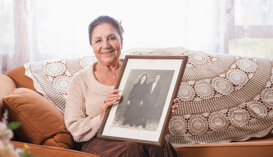 Mujer hispana de mediana edad sosteniendo una foto antigua de una pareja
