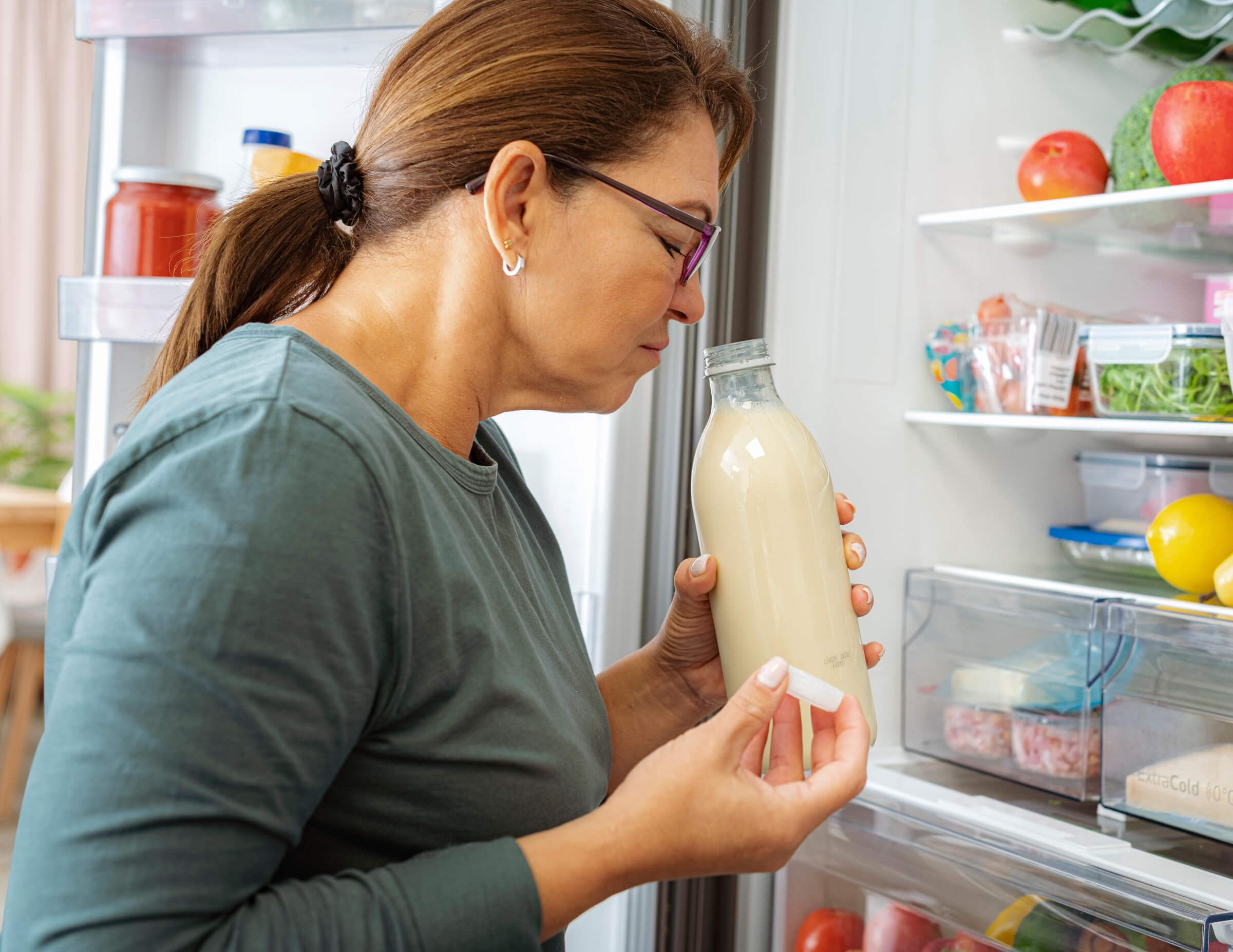 Photo of a woman smelling a bottle of milk