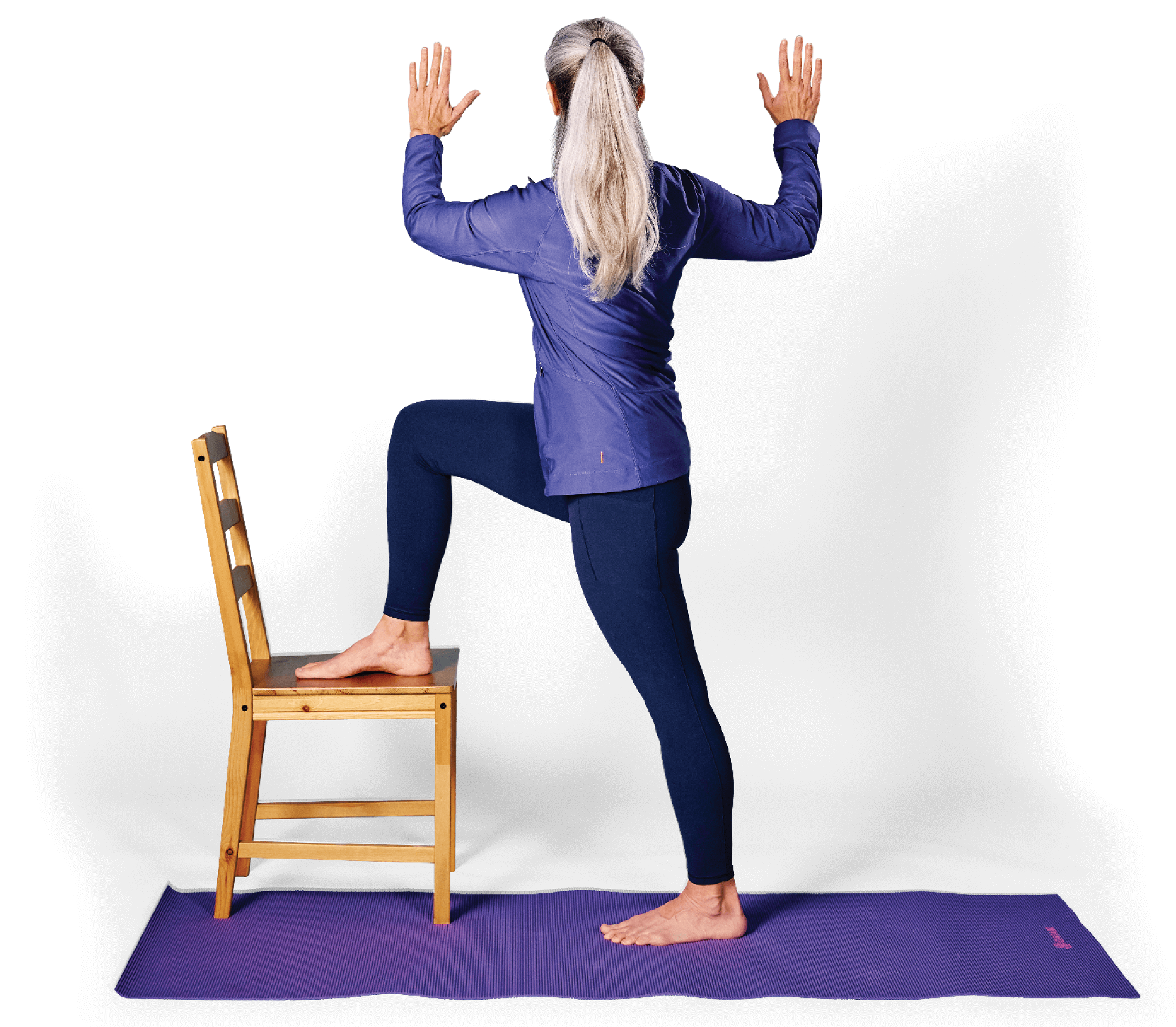 Photo of a woman in Standing Twist 2 yoga pose, with one foot resting on the seat of a chair