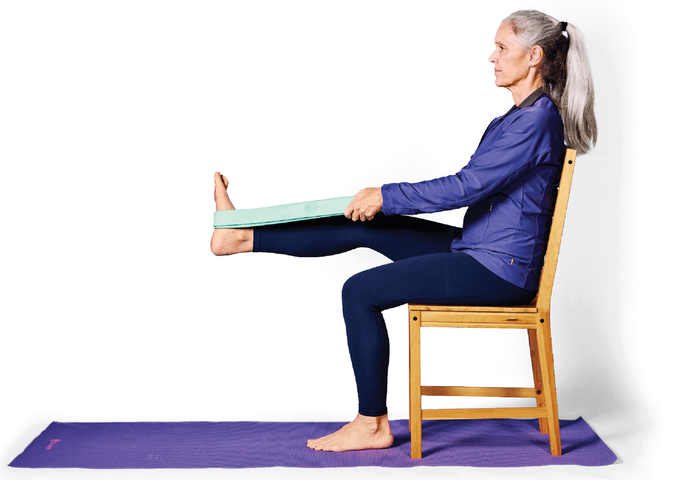 Photo of a woman sitting in a chair, with one leg straight out and supported by a resistance band
