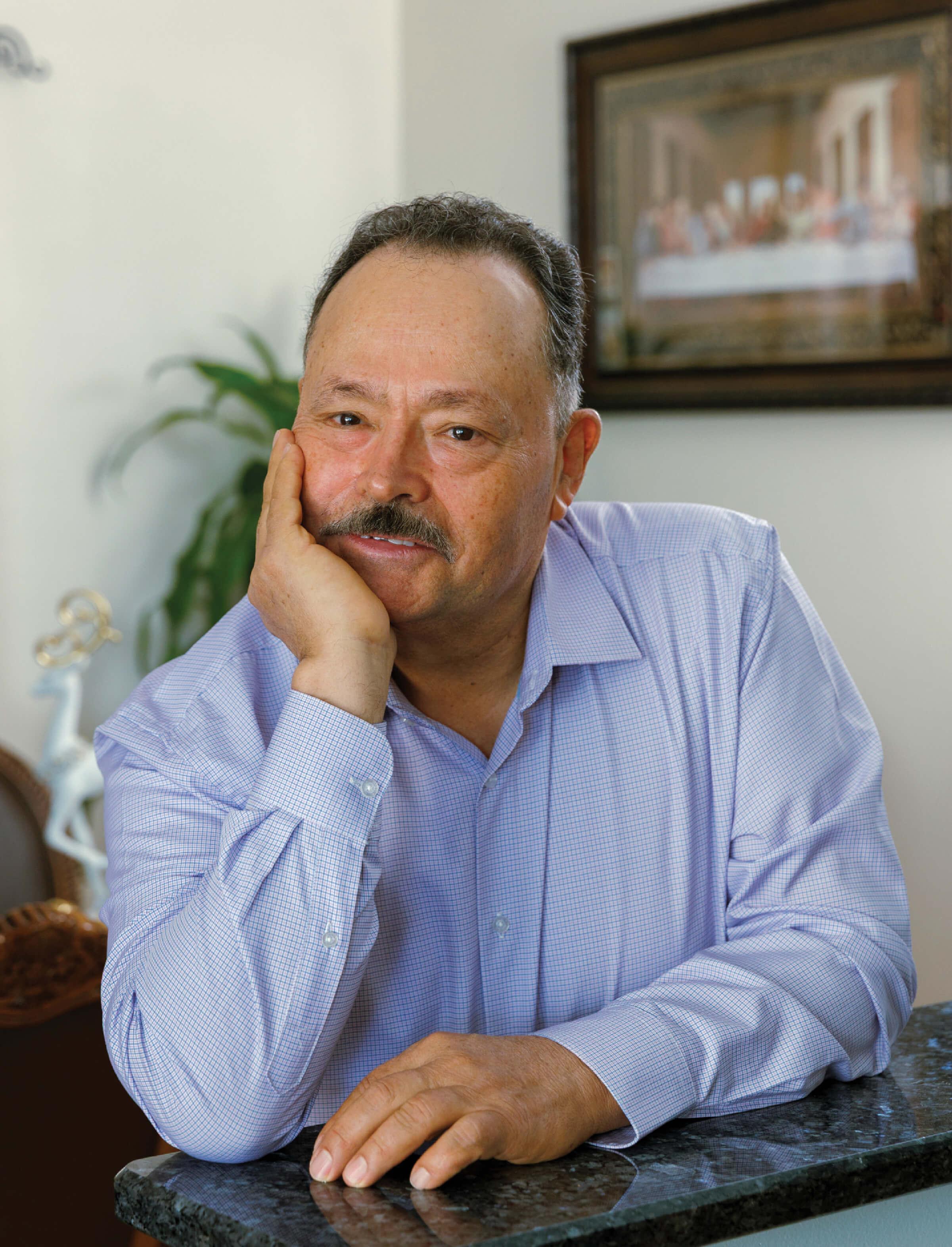 Portrait of Elpidio Gutierrez at 68 sitting at a table.