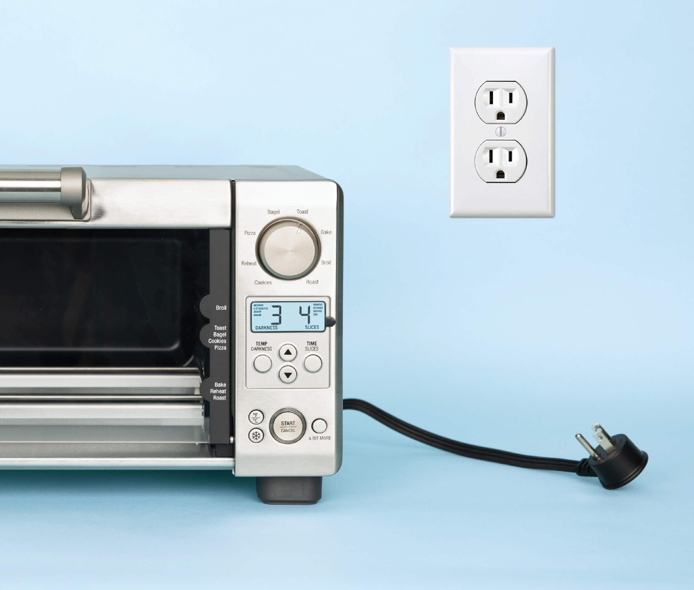 A toaster oven unplugged next to an electrical outlet.