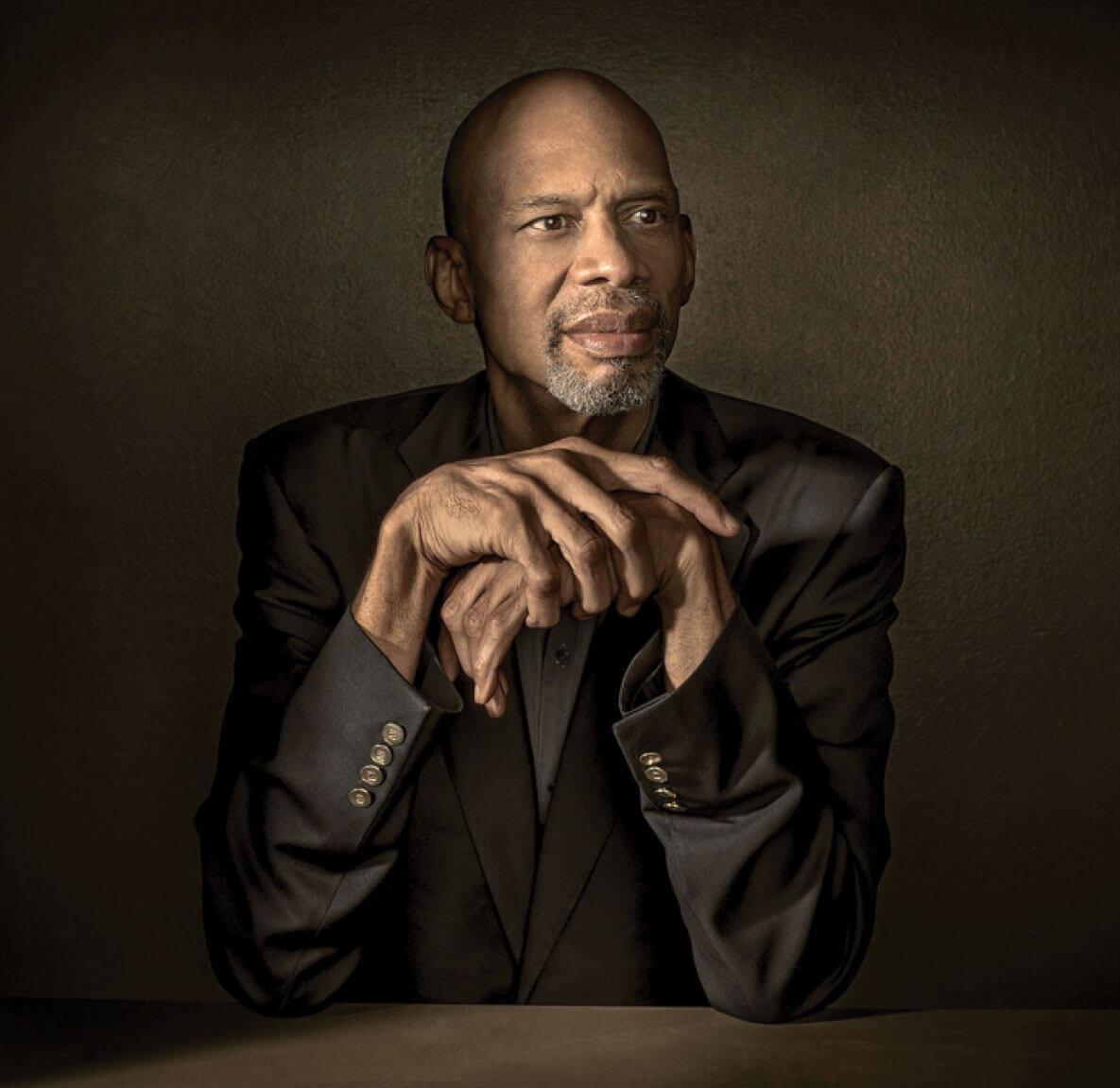 Kareem Abdul-Jabbar with elbows on a table and hands folded