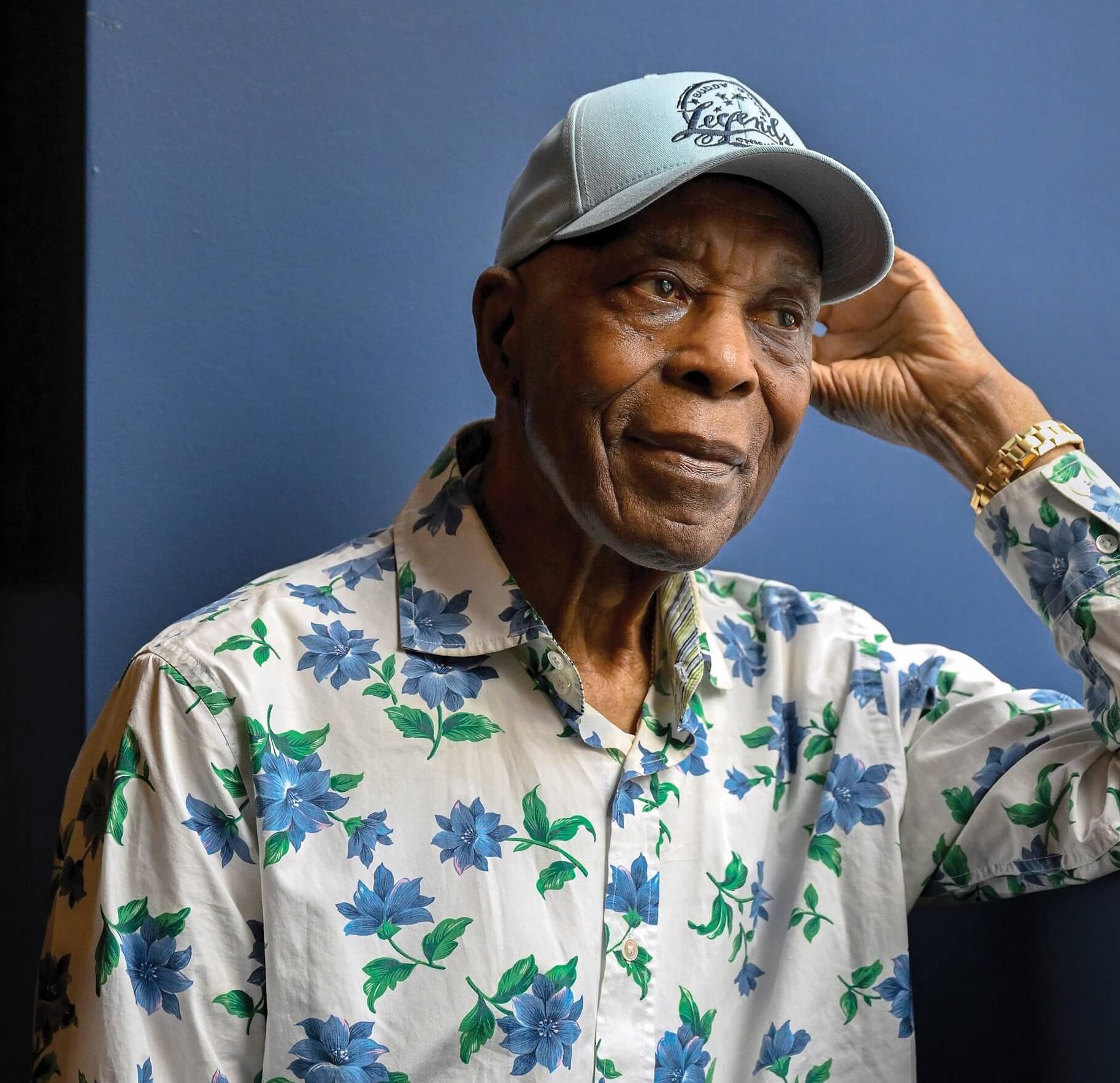 Portrait of Buddy Guy. He is wearing a white shirt with blue and green flowers on it