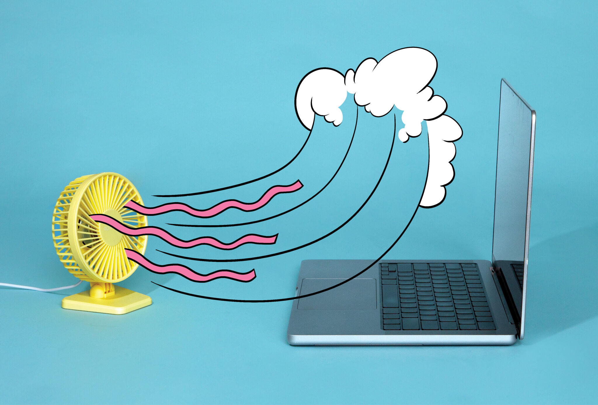 Photograph of a laptop with a fan blowing air at it 