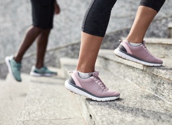 Pair of feet in sneakers walking up steps outside