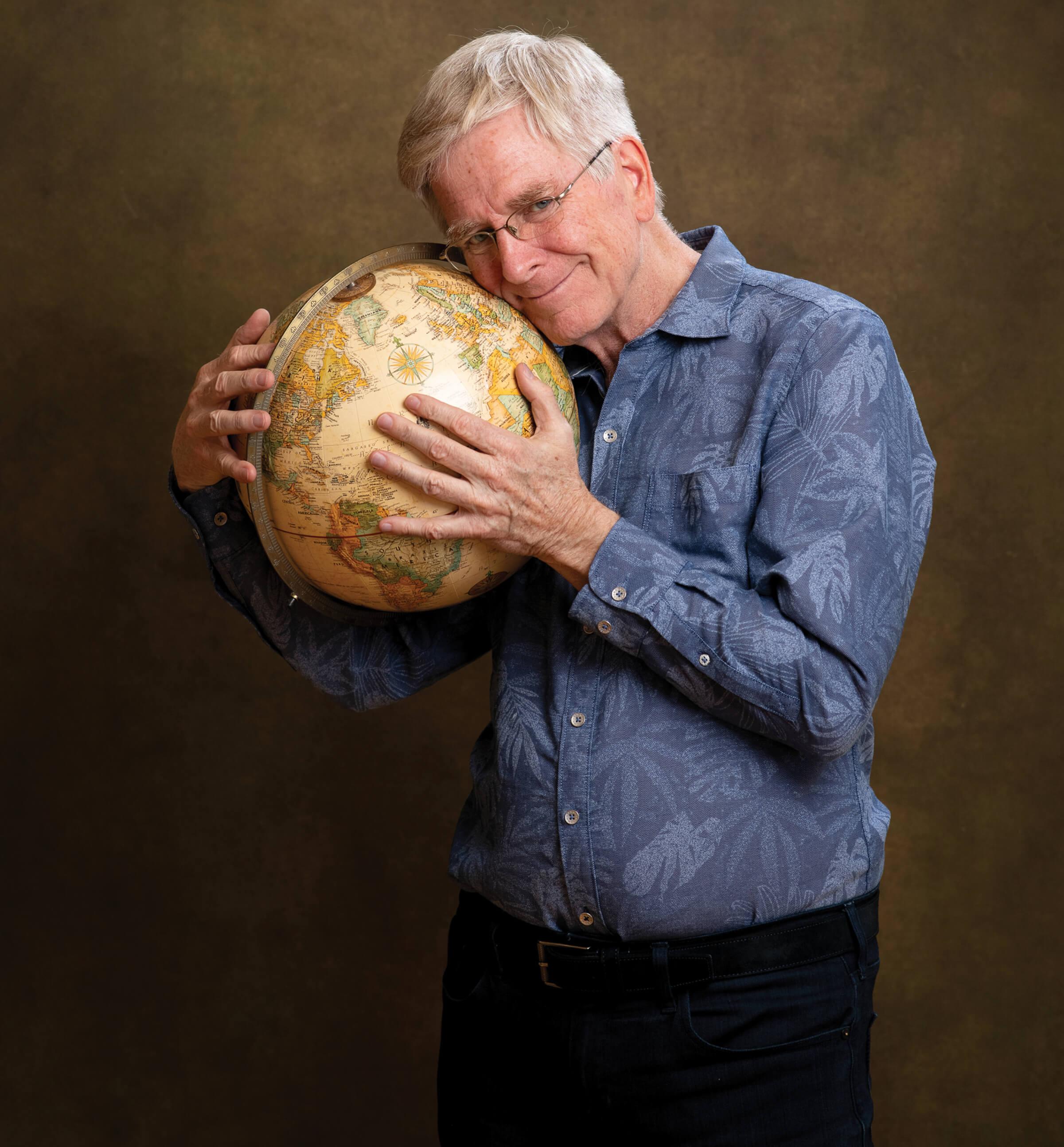 Photo portrait of Rick Steves holding a globe