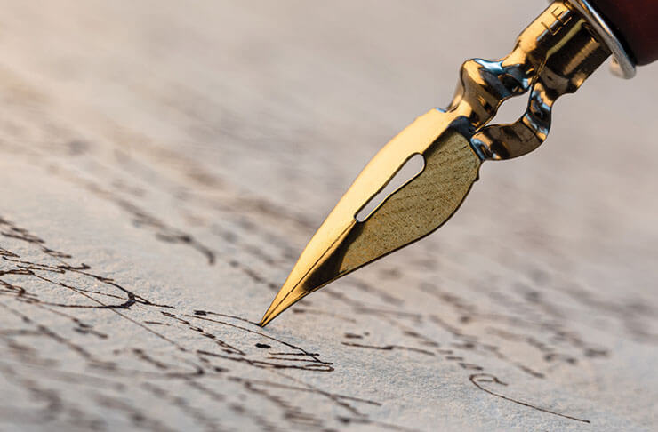 Photo of a pen writing in cursive