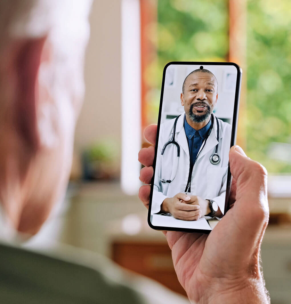 Photo of man olding phone, with doctor on video call