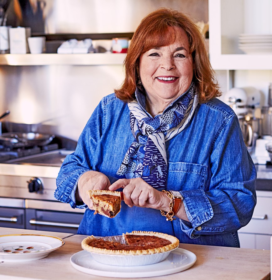 Photo of Ina Garten in a kitchen, butting into a pie