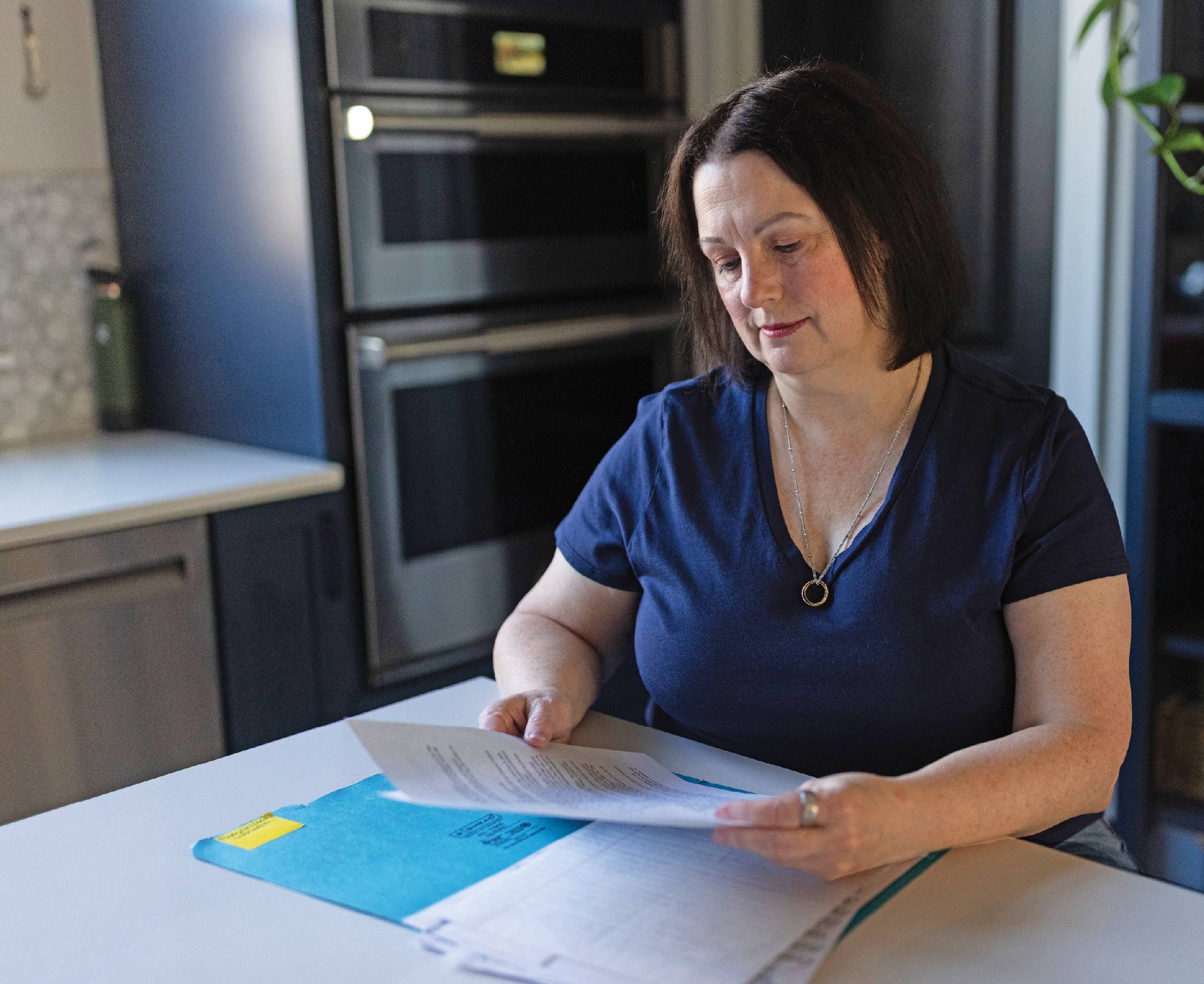 Photograph of Jay Frank-Collins sitting at a table and reading paperwork.