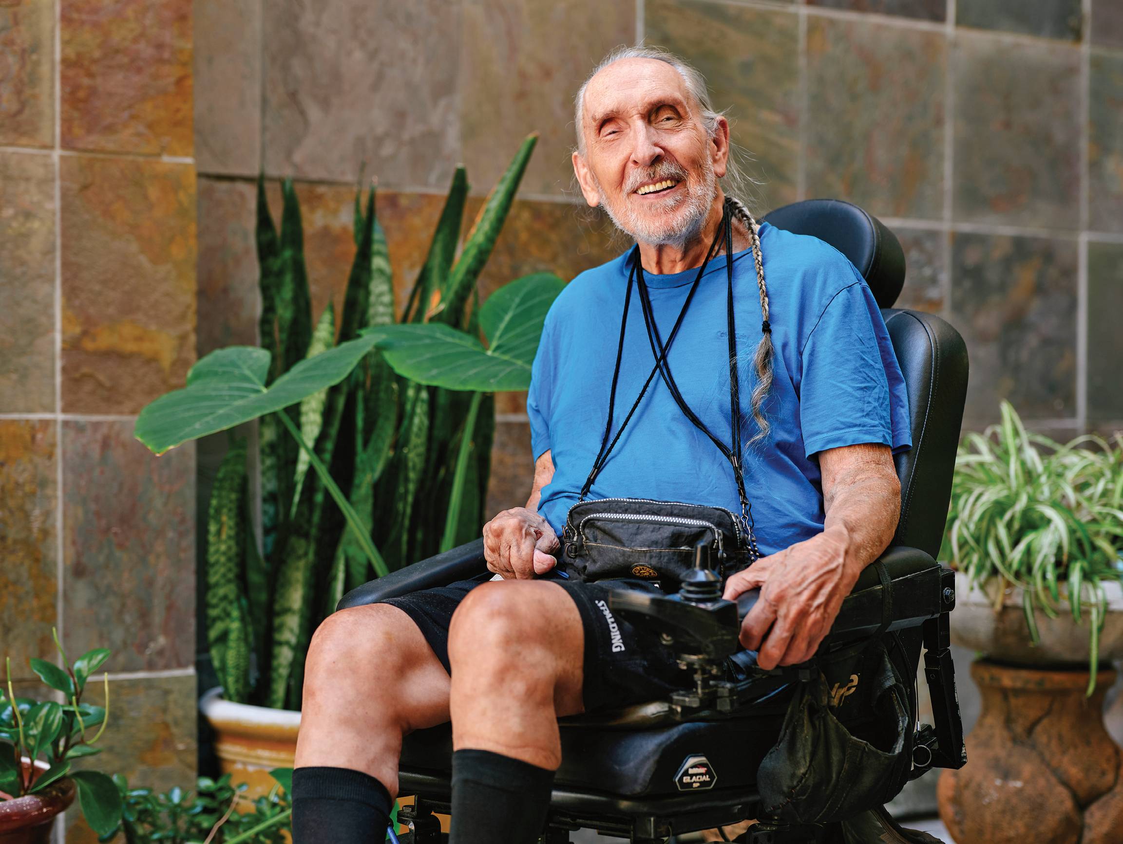 Photograph of Leon Christensen, smiling at the camera surrounded by plants.