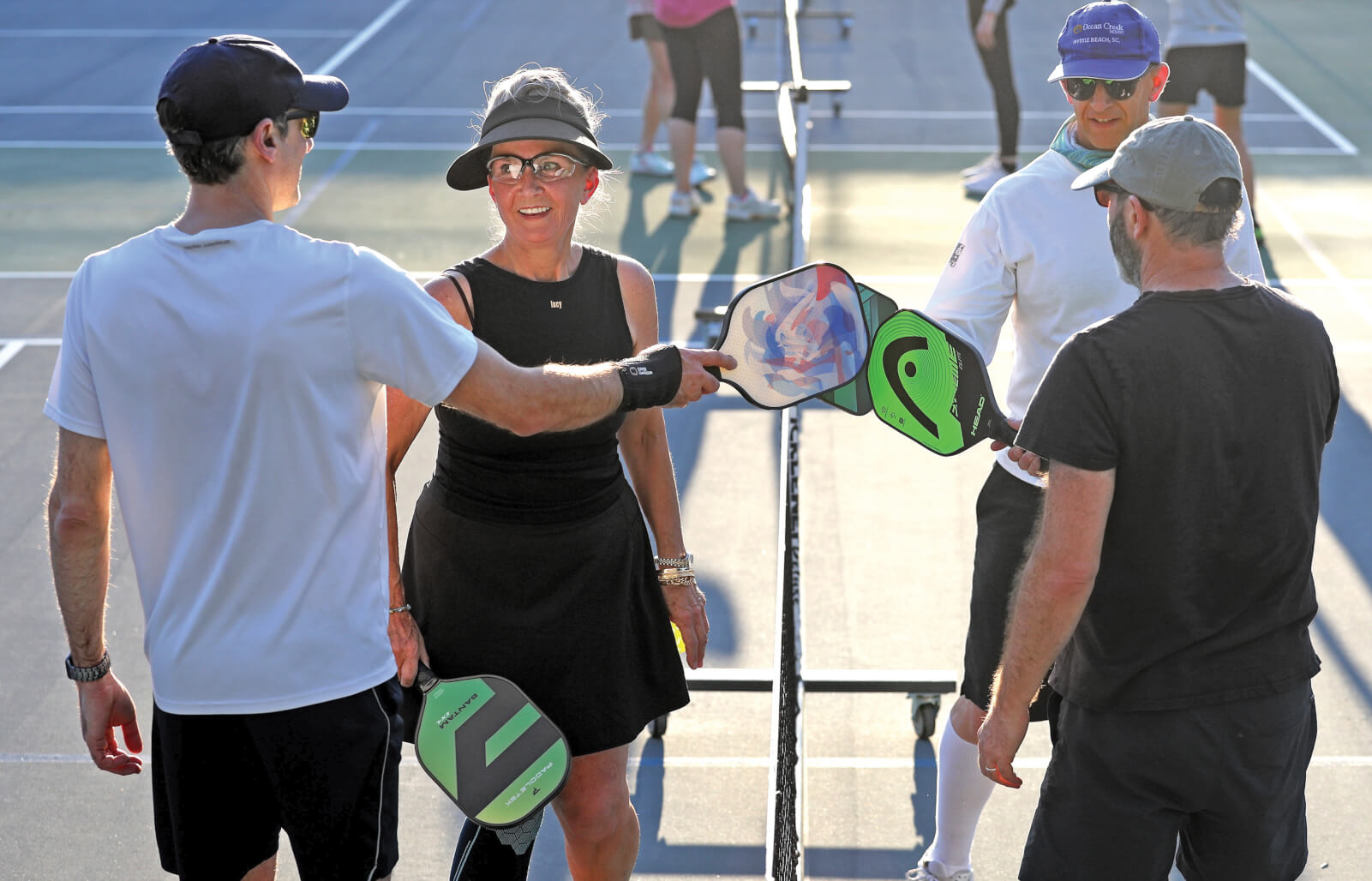 Photo of a pickleball foursome touching their paddles together