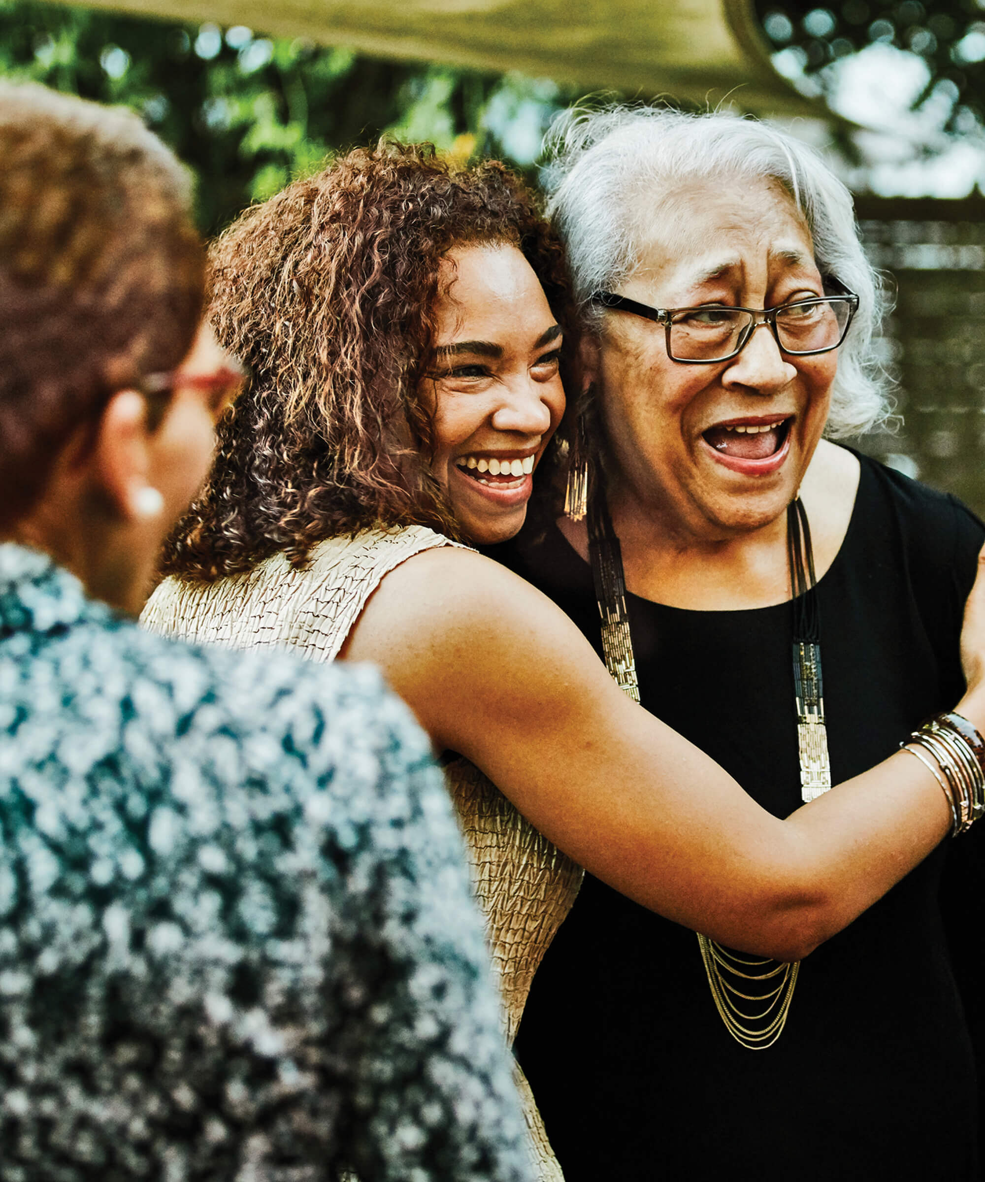 A young girl laughing and giving an older woman a hug.