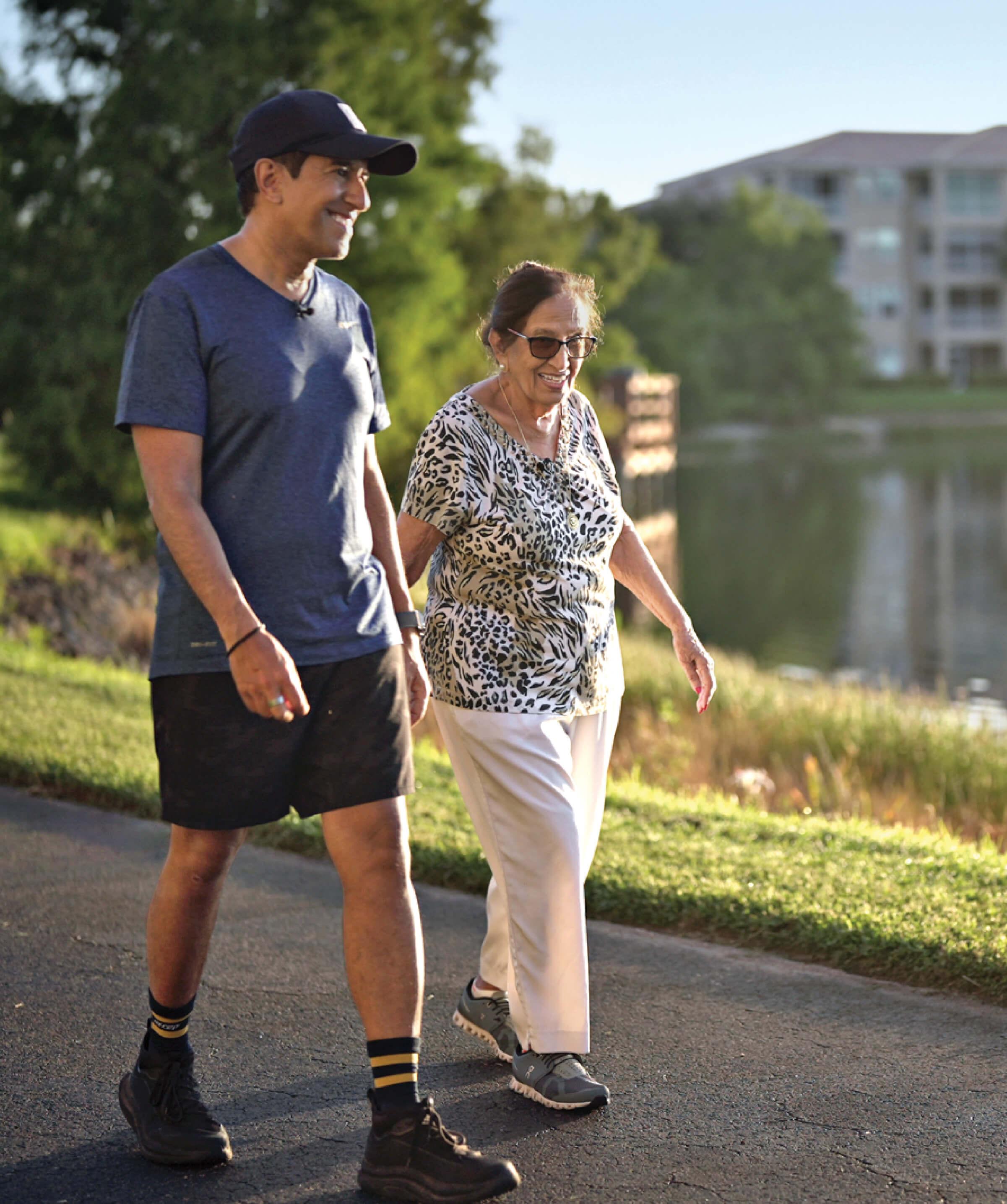 Middle aged Sanjay Gupta walking with his mother, Damyanti Gupta.