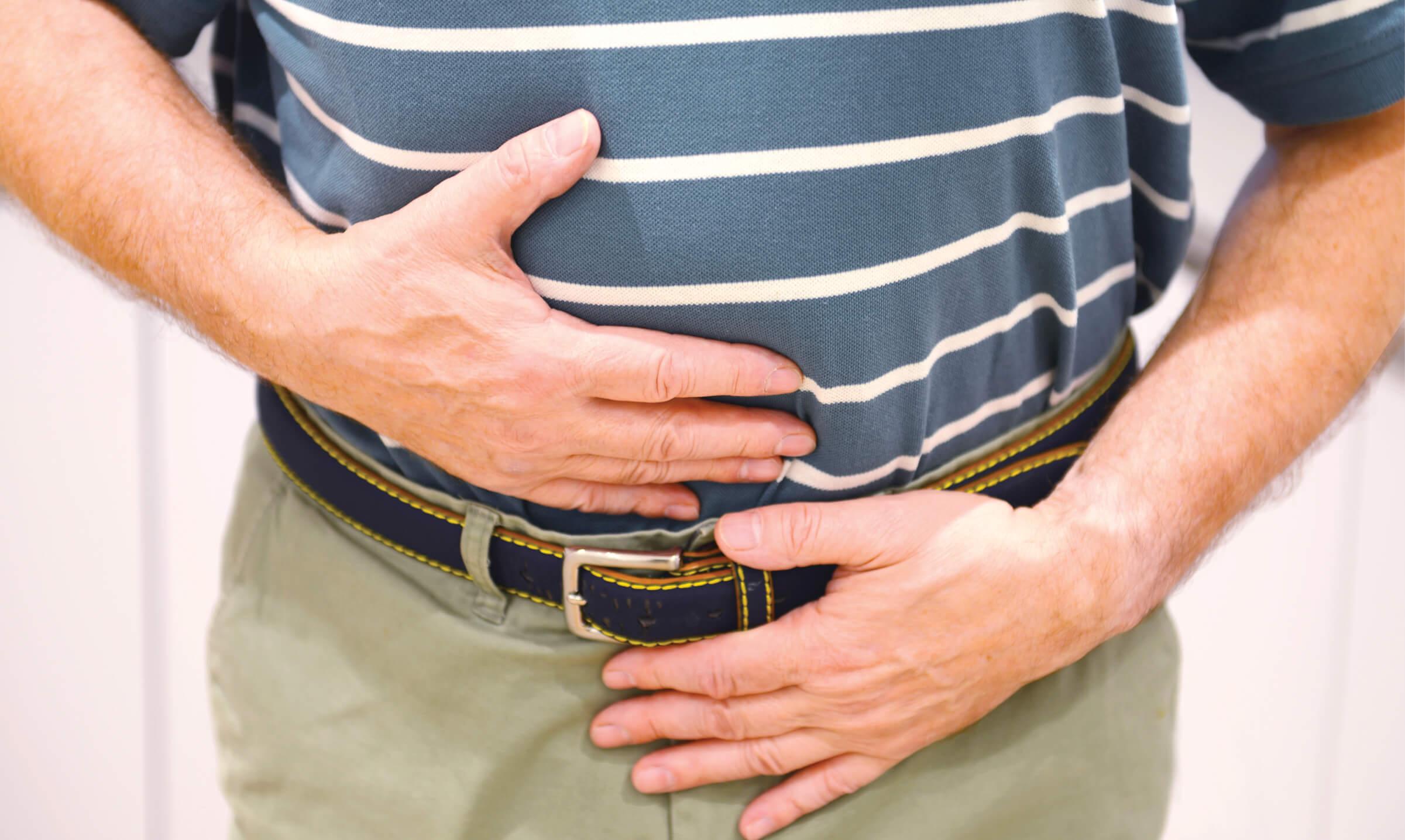 Image of an older man holding his stomach in pain