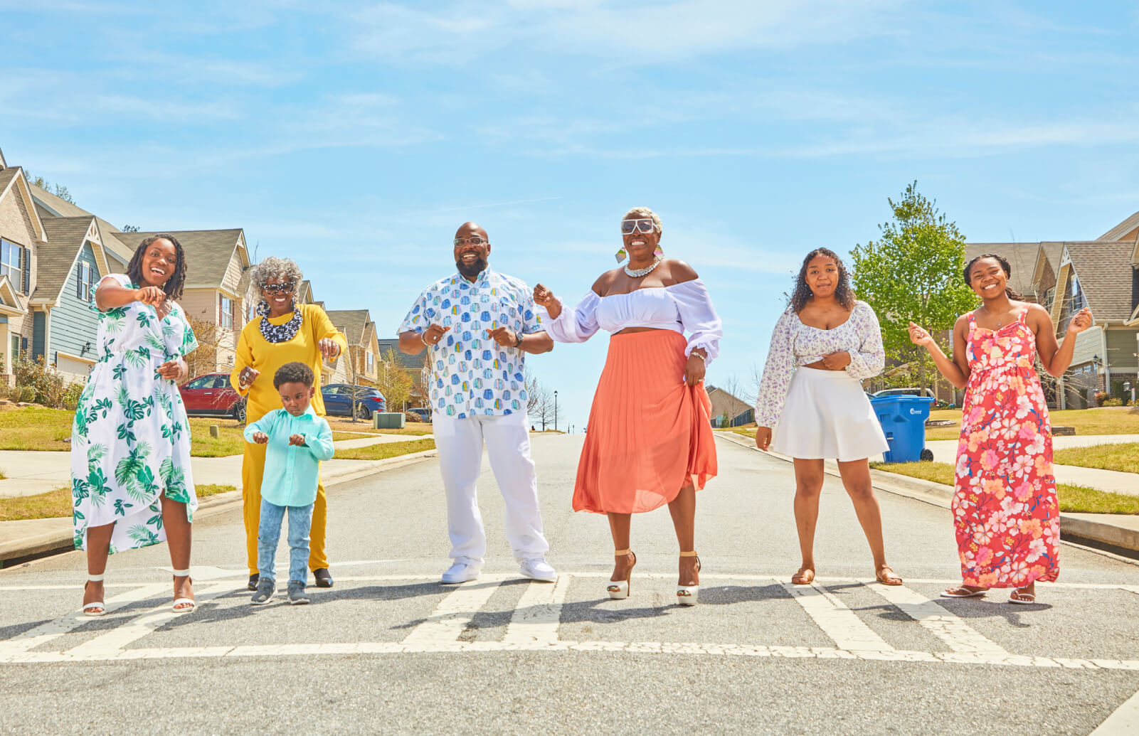 Photo of Marie Moring dancing in the street with six of her family members outside of their home. 