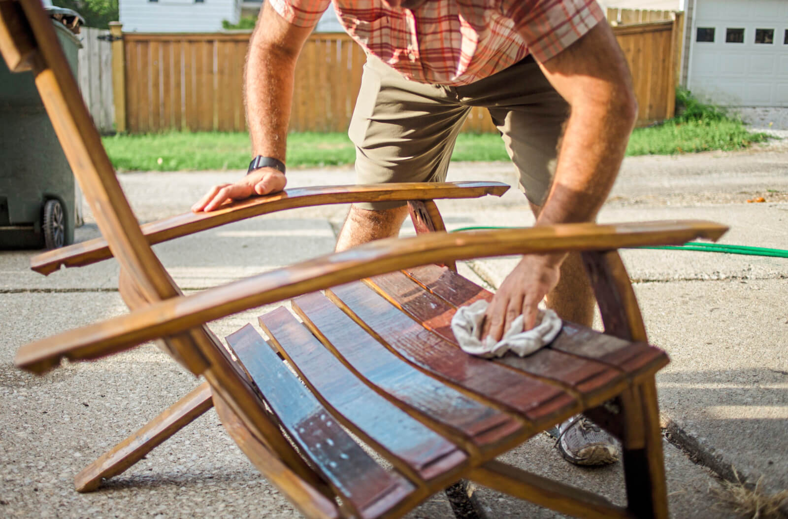 Photo of a man conditioning a wooden outdoor chair