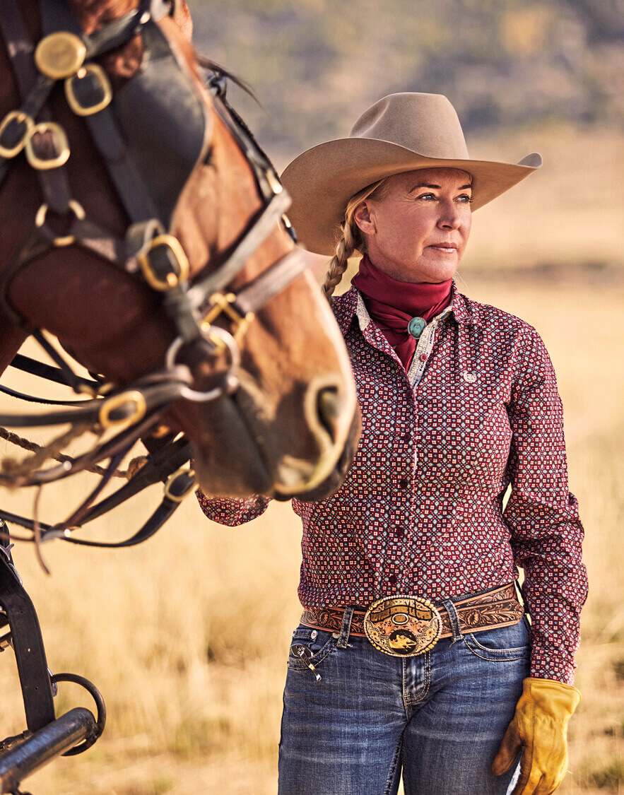 Photo of Diane Branagan in a field with one of the horses she trains.