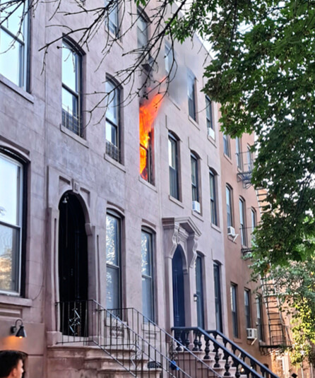 Photo of fire flames bursting through a building window.