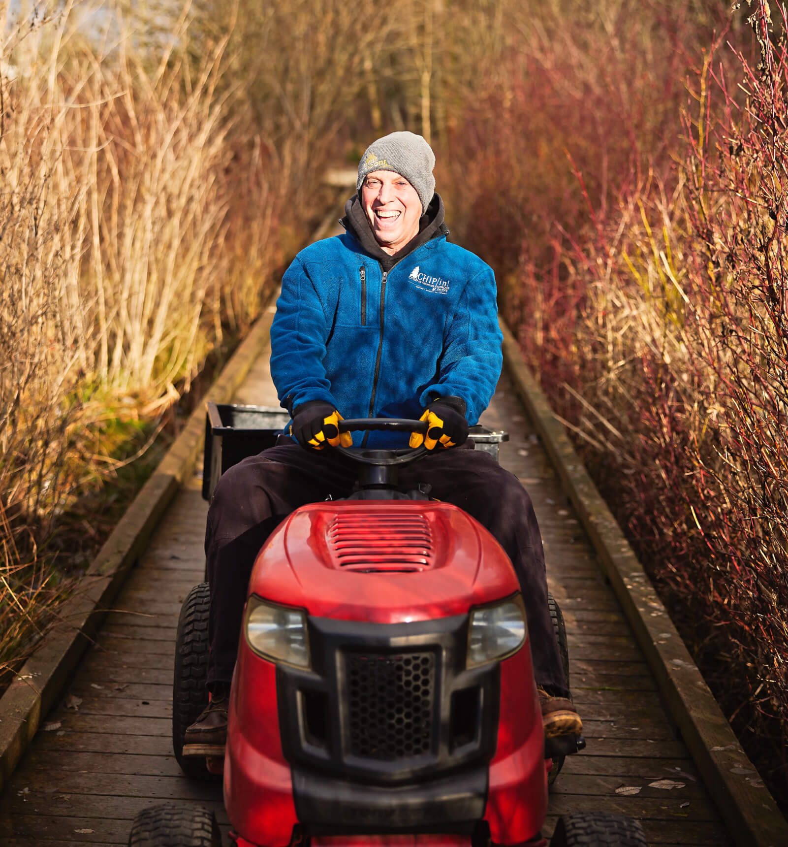 Photo of Danny Patnode riding a small maintenance tractor on a boardwalk in McKinley Park.