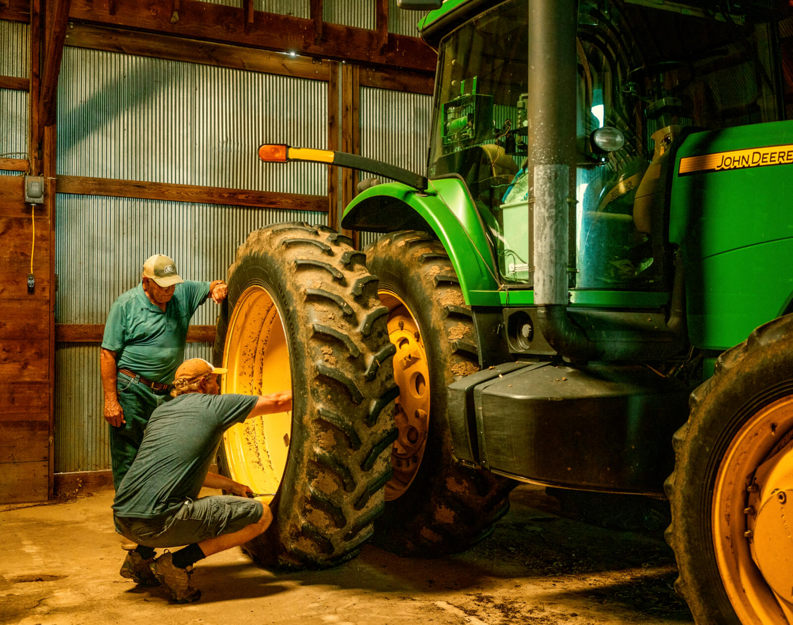 Photo of 2 men inspecting the large wheel of a tractor