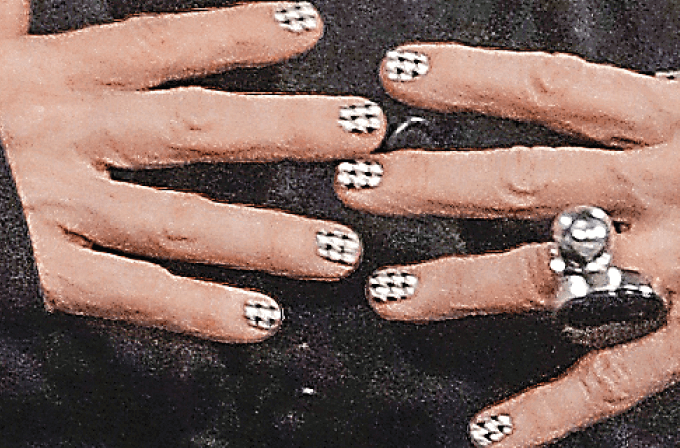 Photo of hands with checkerboard painted fingernails and one finger wearing a chunky silver ring