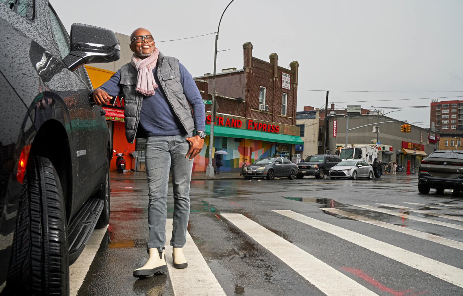 Photo of Fritz Sam leaning against his car in a Brooklyn intersection.