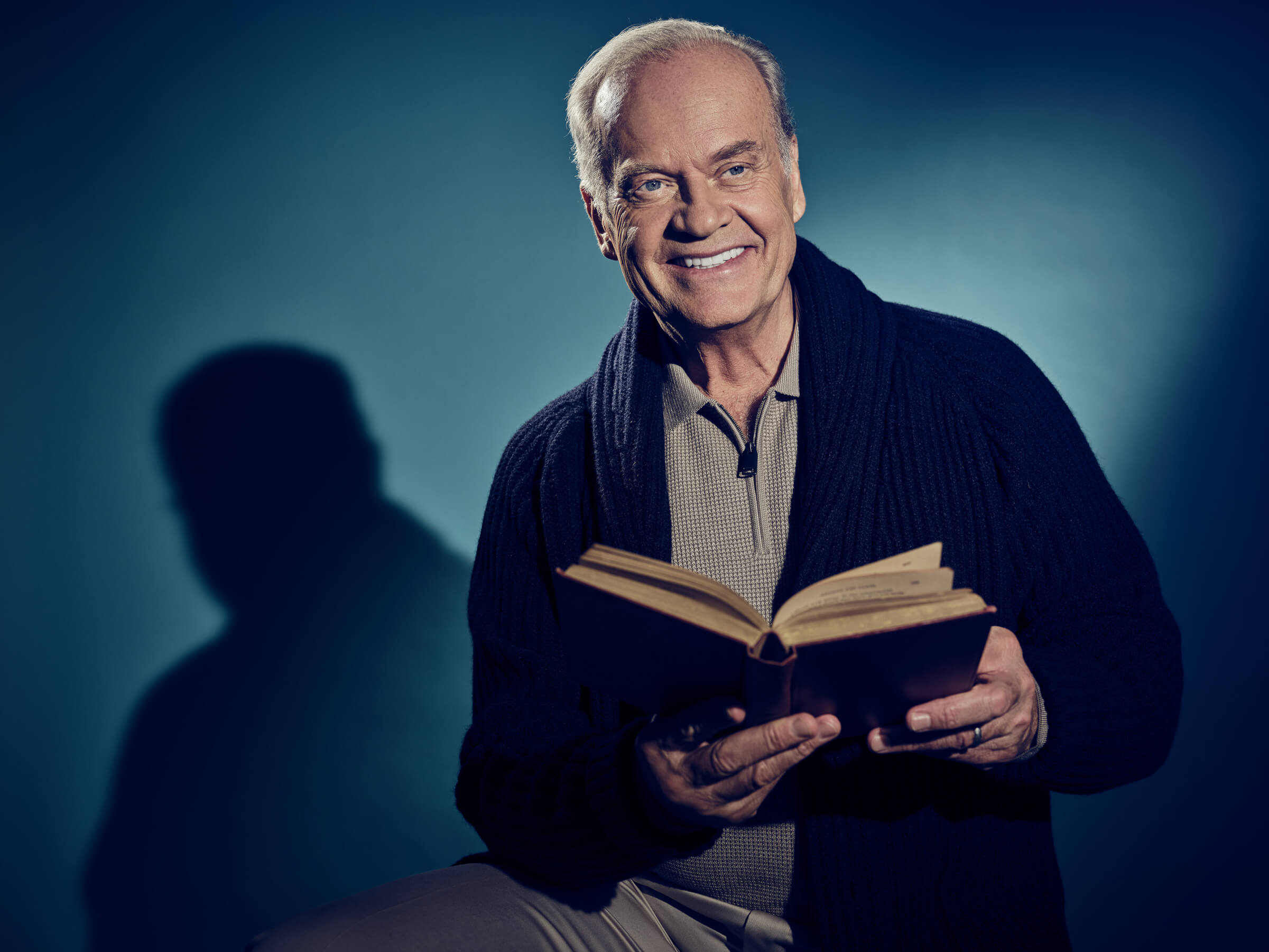 Photo of a smiling Kelsey Grammer holding a book