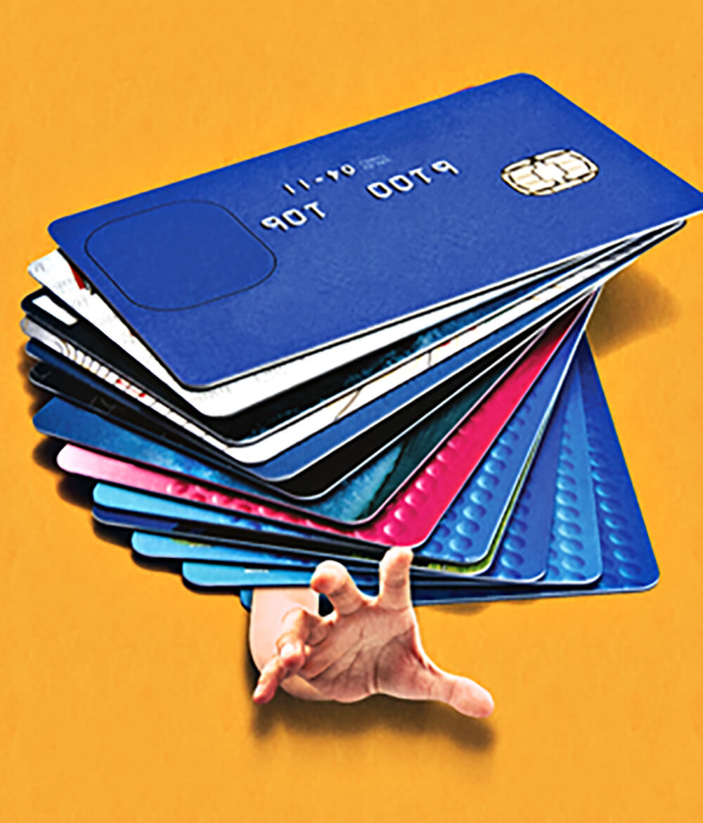 Conceptual photo illustration of a hand reaching out from under a pile of credit cards