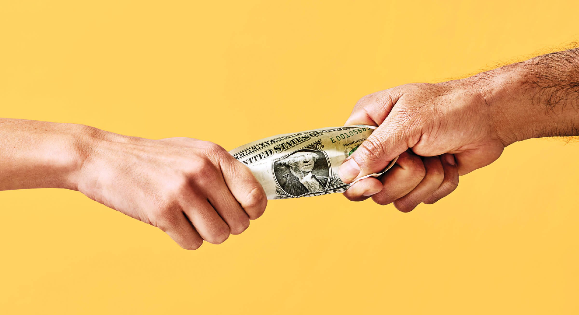 Photo of two hands pulling on a dollar bill between them