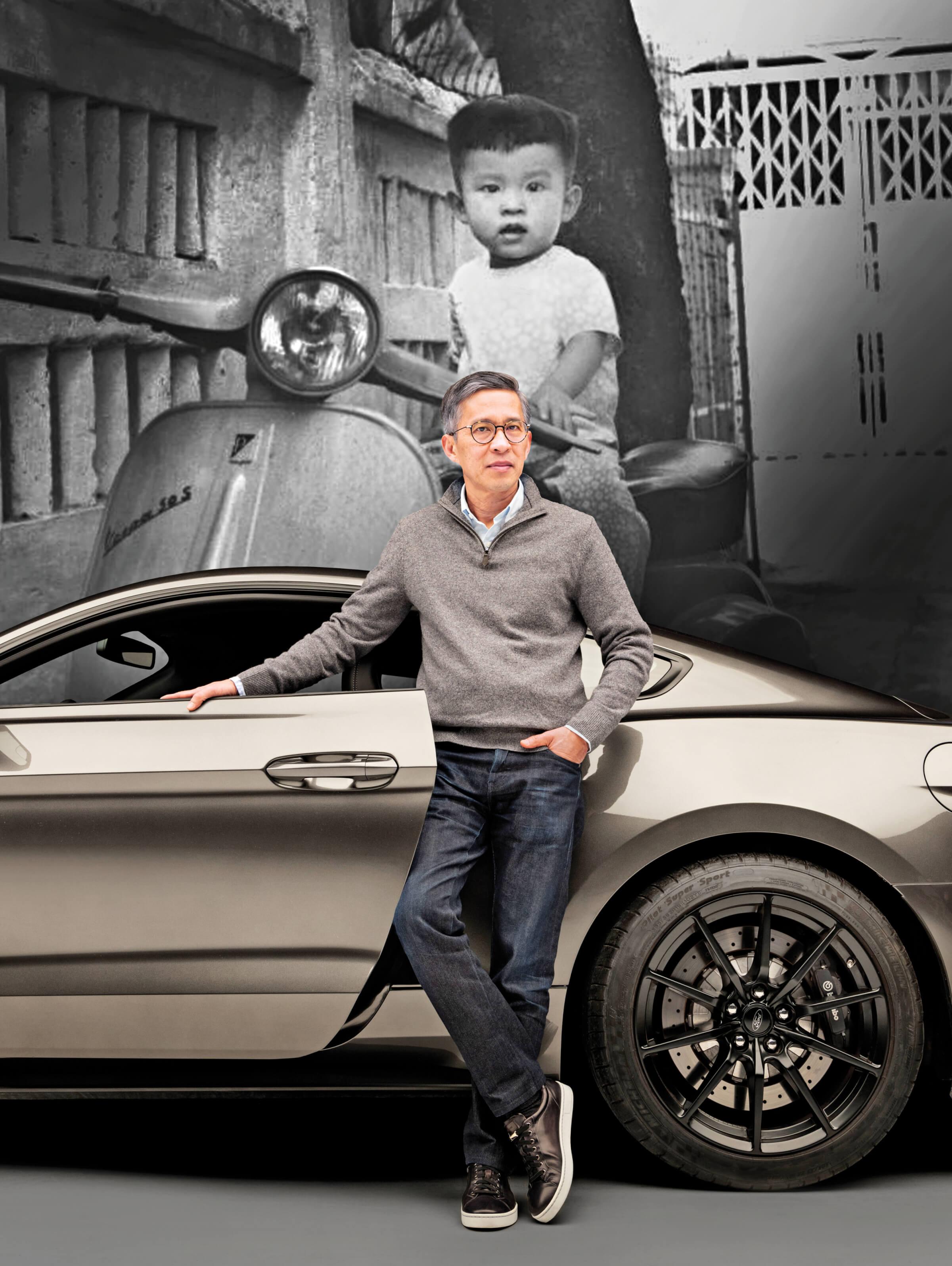 Photo of Hau Thai-tang today, standing in front of a silver Ford Mustang