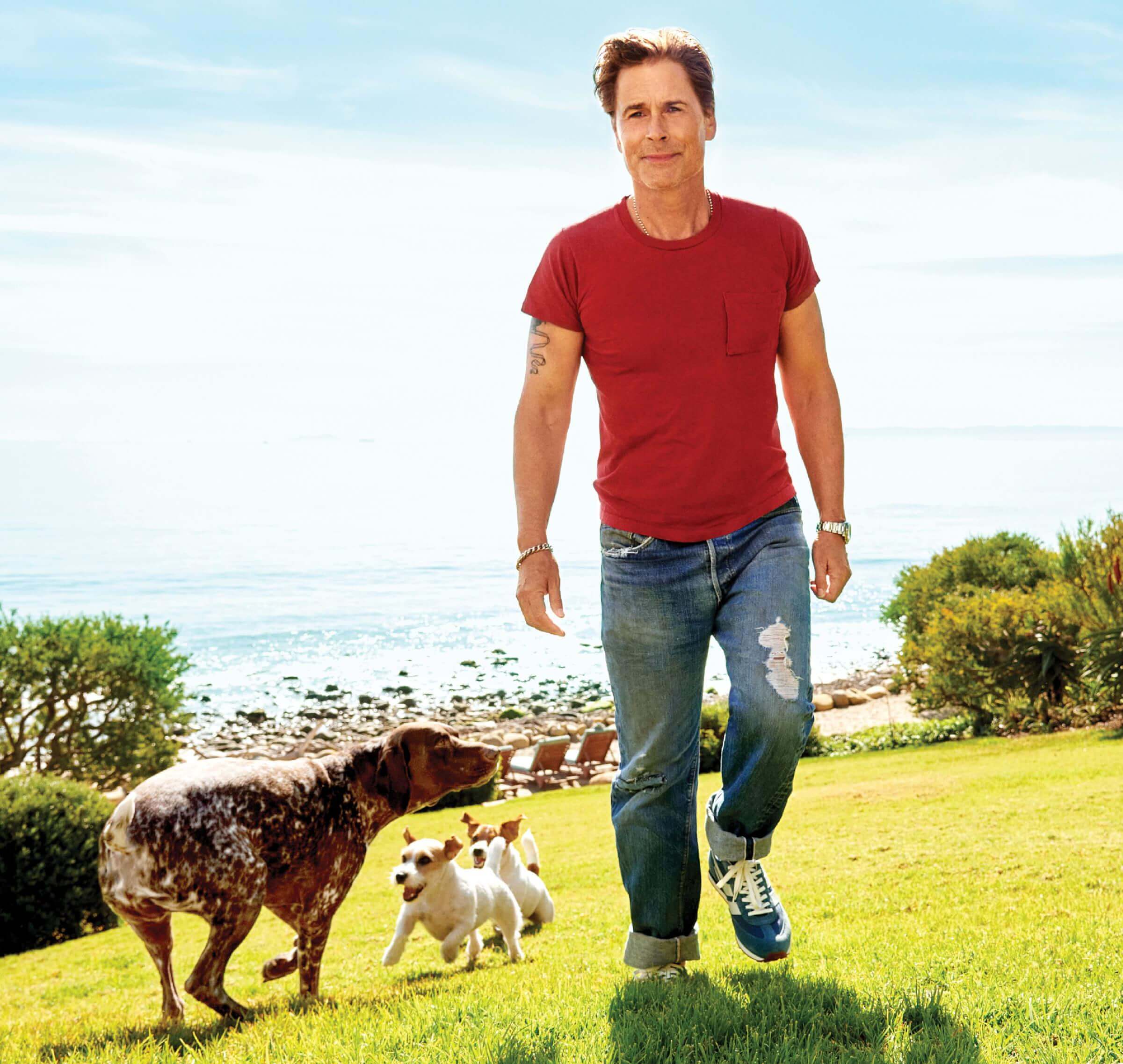 Photo of Robe Lowe walking in grass with 3 of his dogs