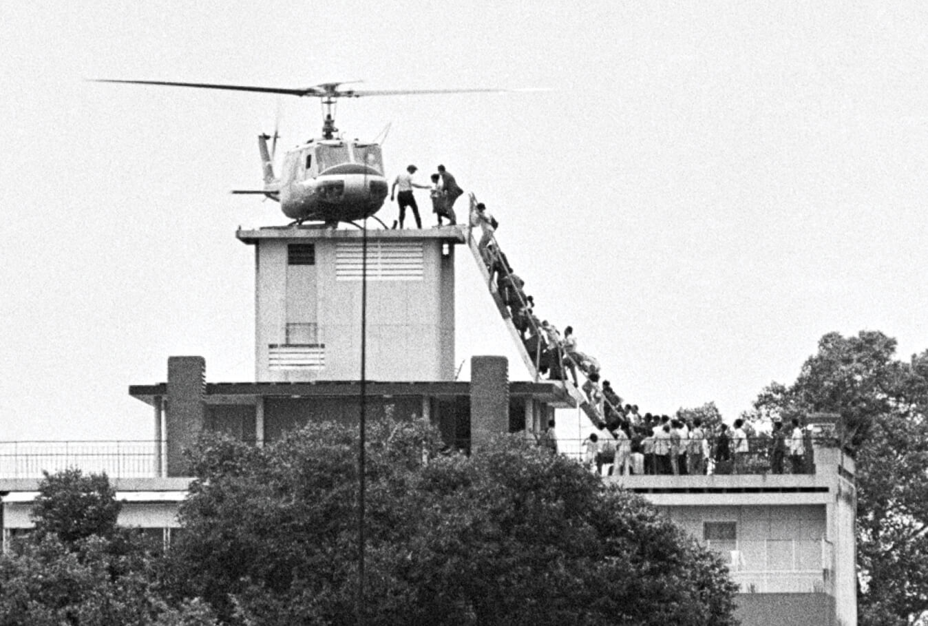 Photo of a helicopter on a roof with people waiting in line to board