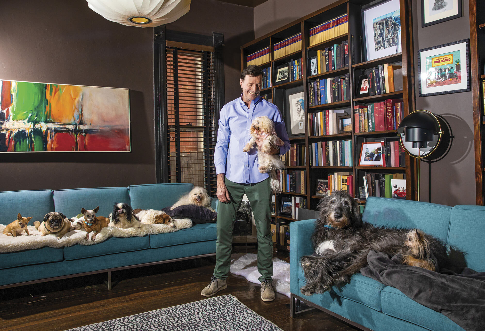 Photo of Steve Greig in his home, surrounded by 9 dogs
