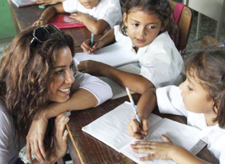 Photograph of Eva sitting at a table and talking to children