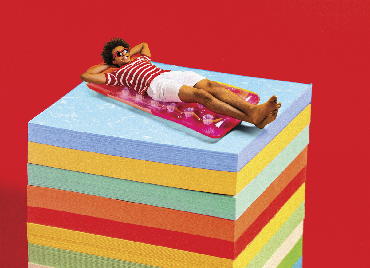 Photocollage of a man lying down on a beach towel on a stack of post it notes