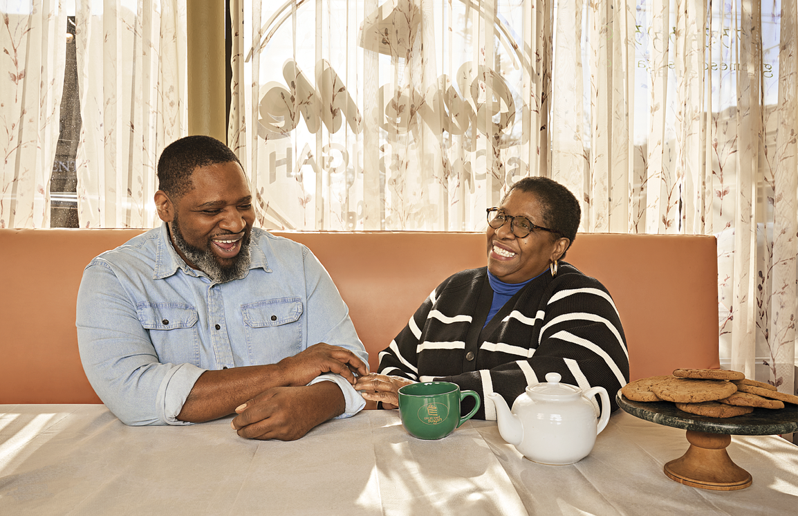 Photograph of Hunter and Lindsey sitting at a coffee shop drinking a cup of tea and laughing and smiling 