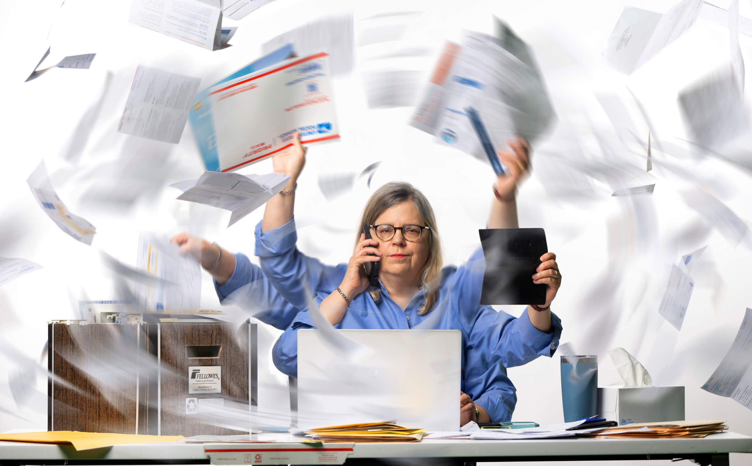 Photo illustration of the author sitting at a desk with a computer, papers, mail, and calculator. A swirl of documents are surrounding her. 