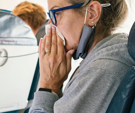 Photo of a woman wiping her nose with a tissue