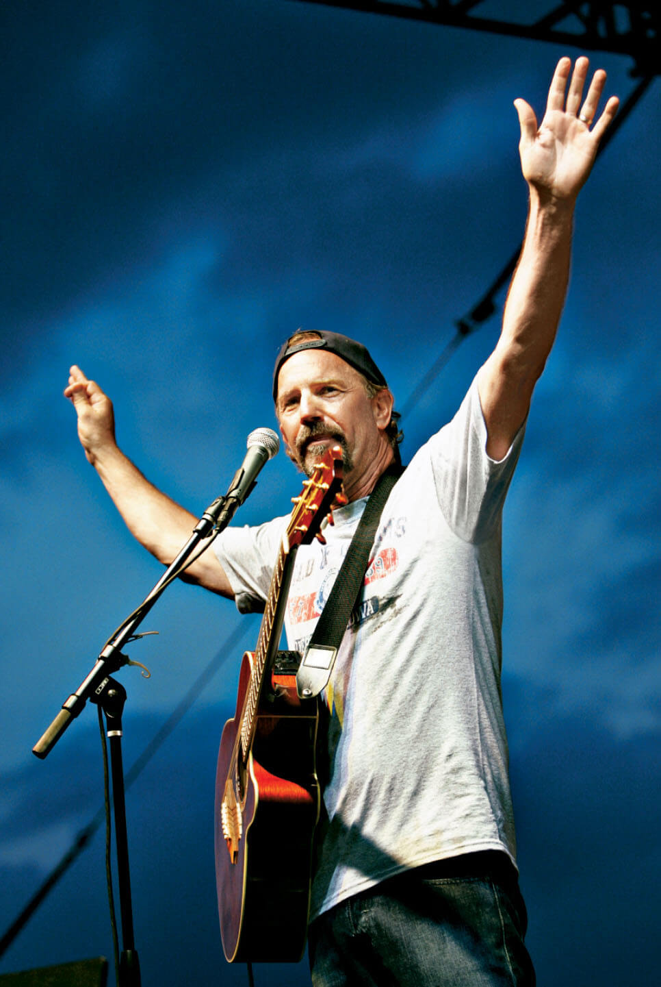 Photo of Kevin Costner on stage with a guitar