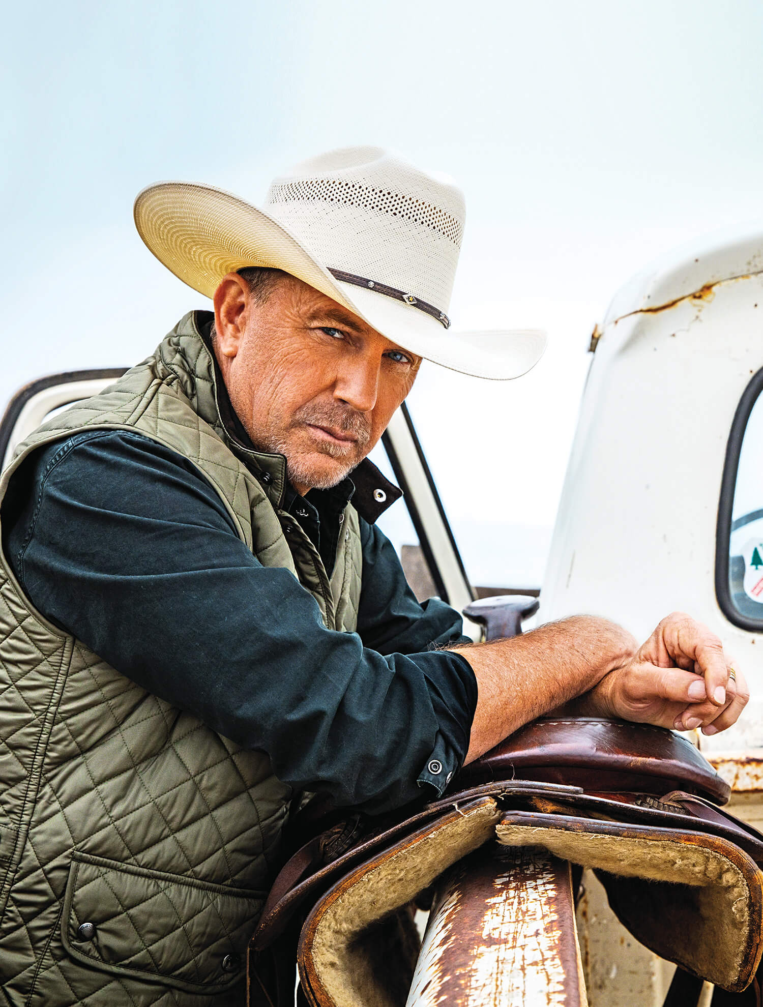 Photo portrait of Kevin Costner leaning on a horse saddle