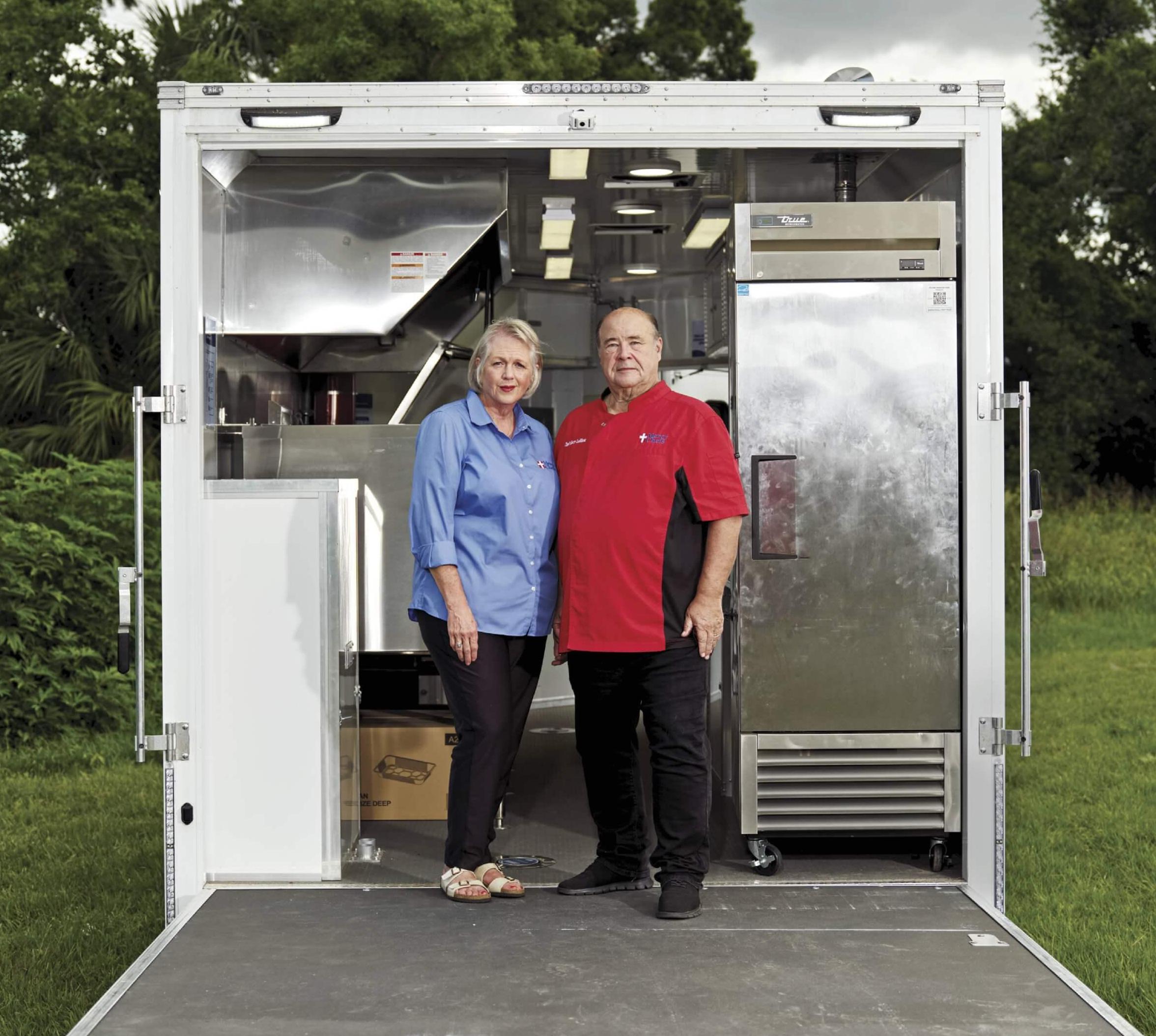 Photo of chefs standing in back of open food truck