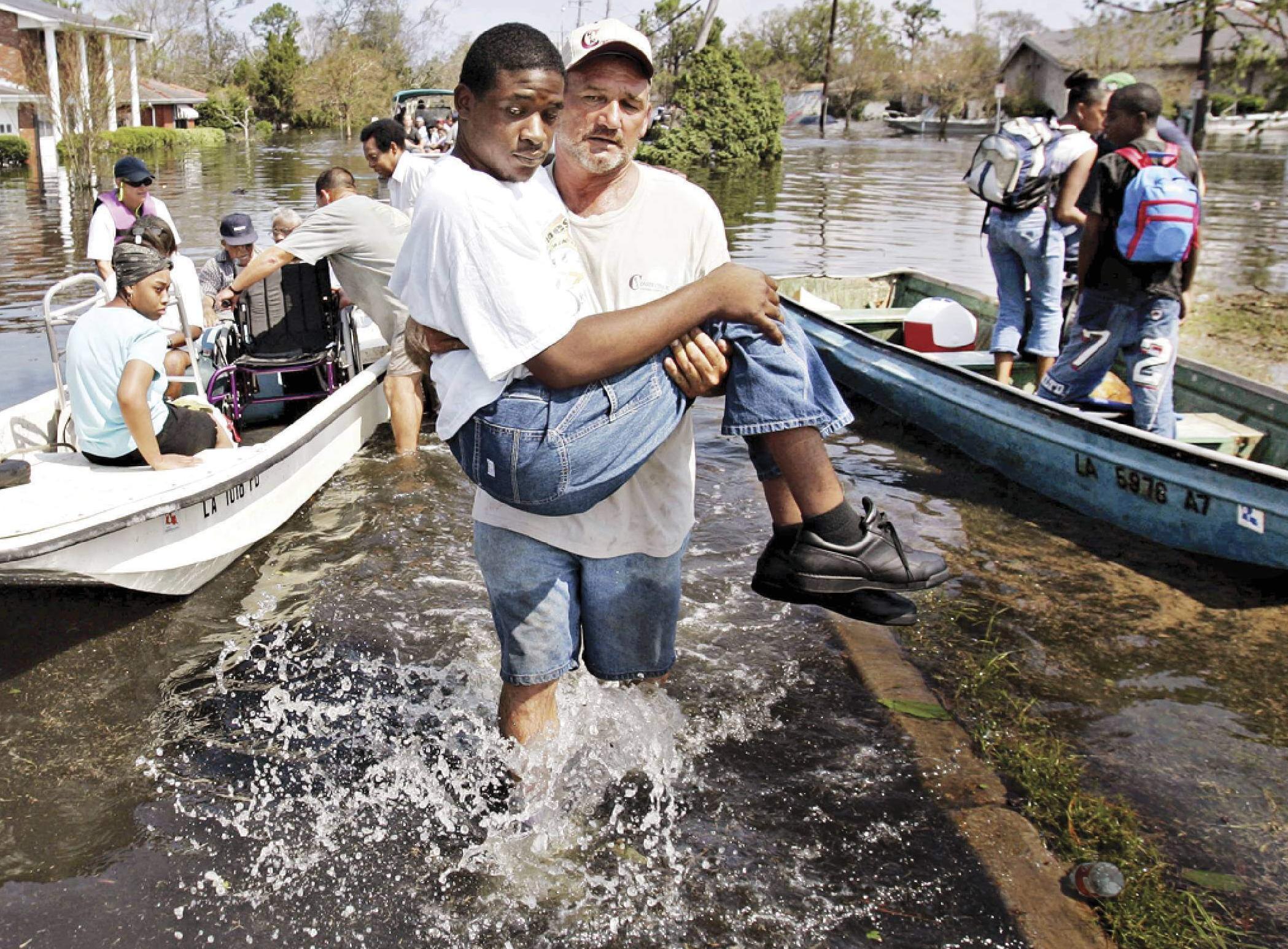 Photo of a man carrying a teenage boy above flood waters